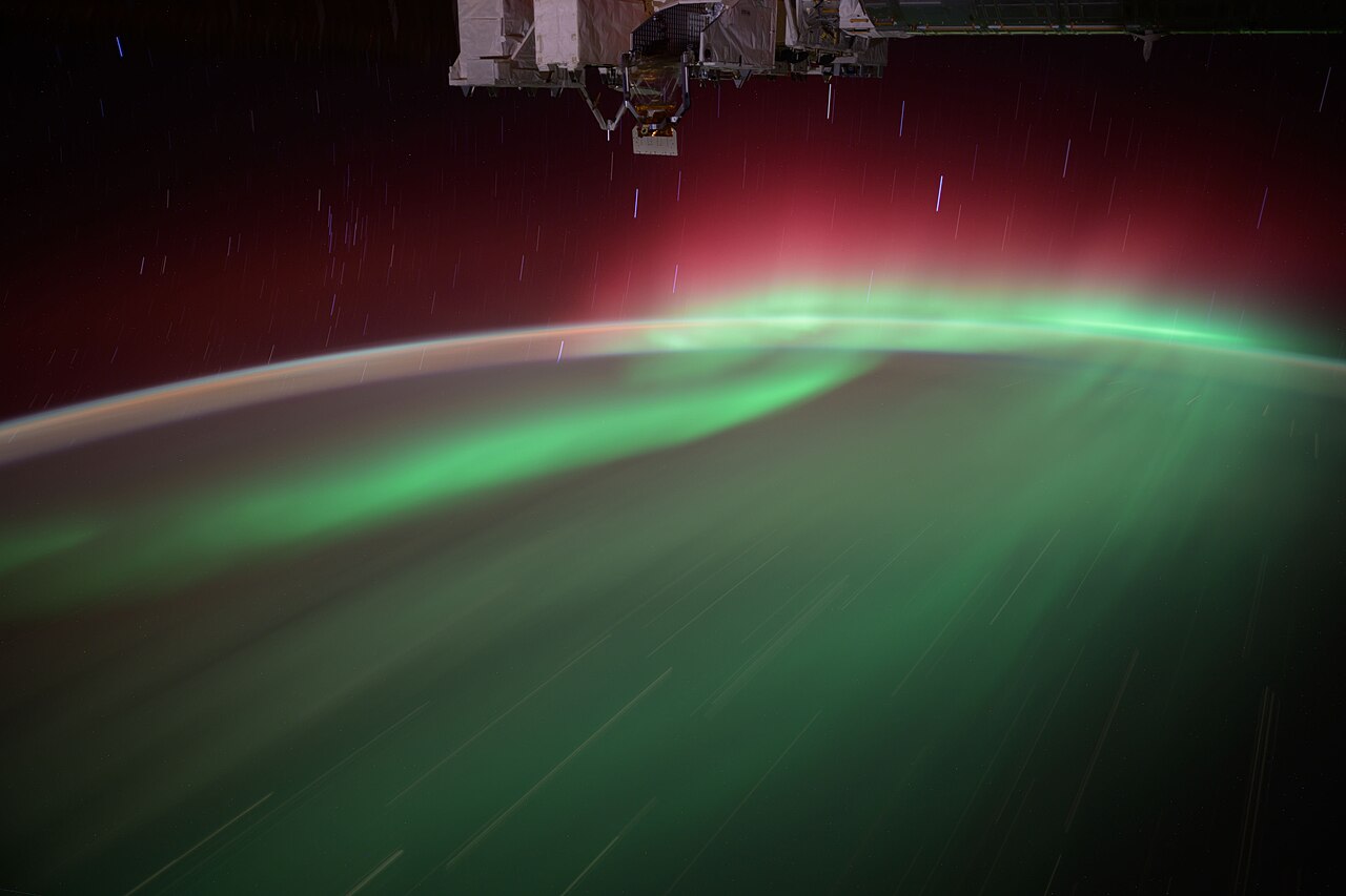 An aurora photographed from the International Space Station. The green below and the red above separate by altitude.