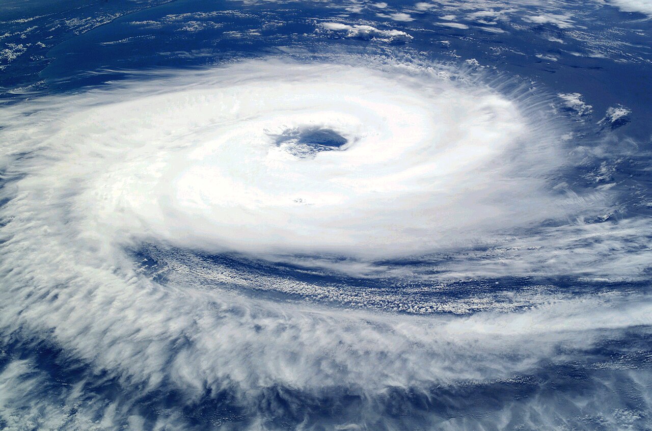 A tropical cyclone (Cyclone Catarina, 2004) seen from the International Space Station — its round eye and spiral cloud bands. A typhoon is at once a disaster and a giant heat engine that turns the warm sea's heat into wind.