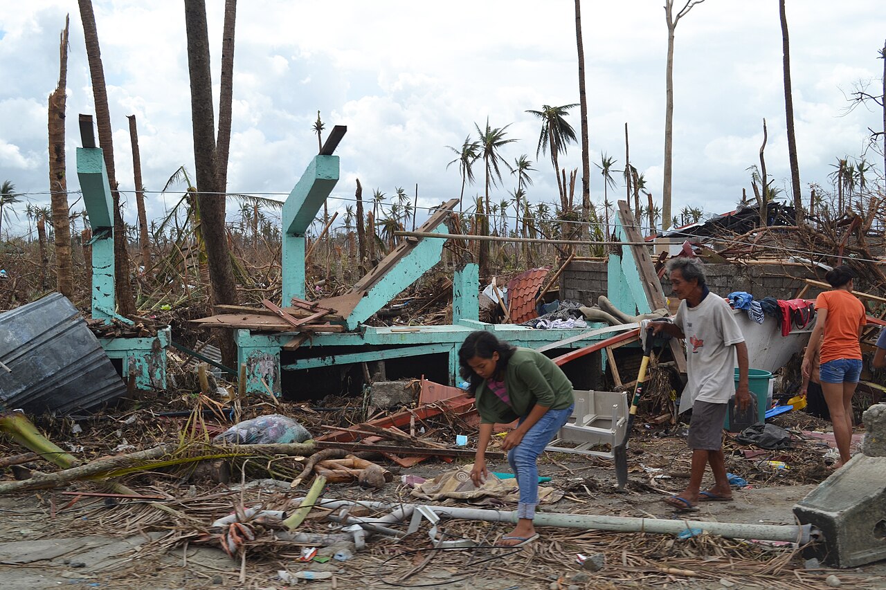 Tacloban in the Philippines after Super Typhoon Haiyan (Yolanda) swept through in 2013. Residents sift through the debris among snapped palm trees and collapsed buildings — the disaster face of a typhoon.