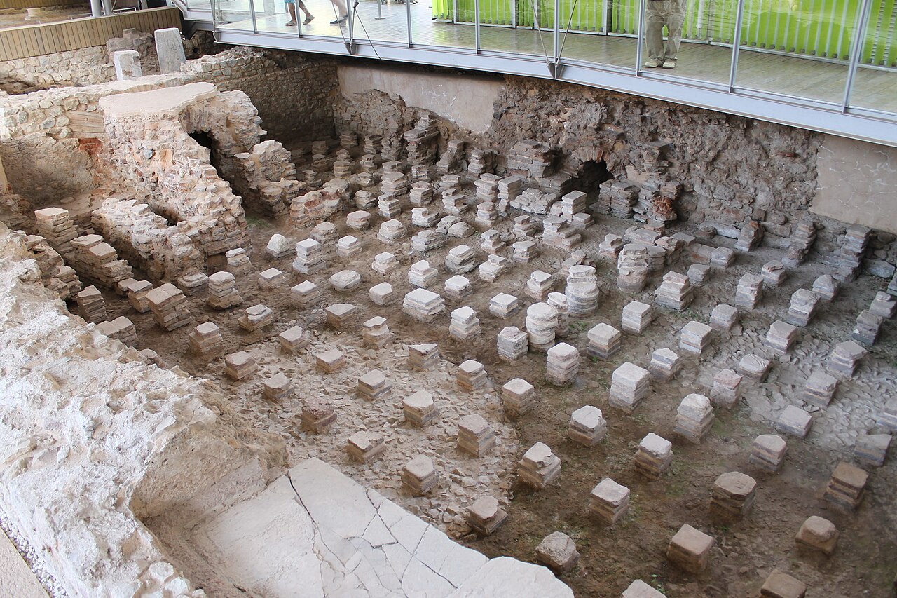 A Roman hypocaust ruin where short brick pillars once supported a raised floor with hot air circulating beneath