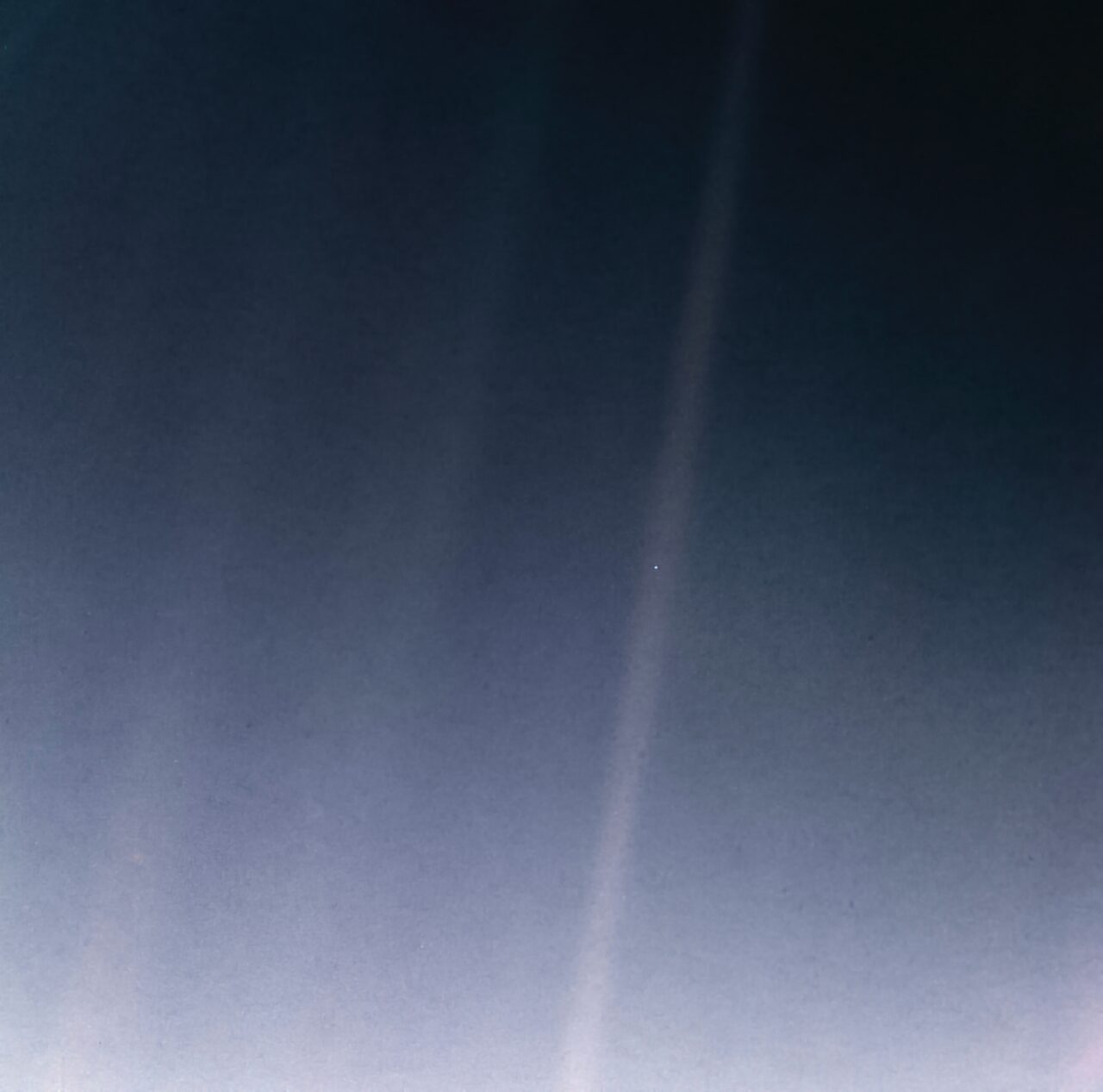 Earth appearing as a tiny point of light within a band of scattered sunlight against black space
