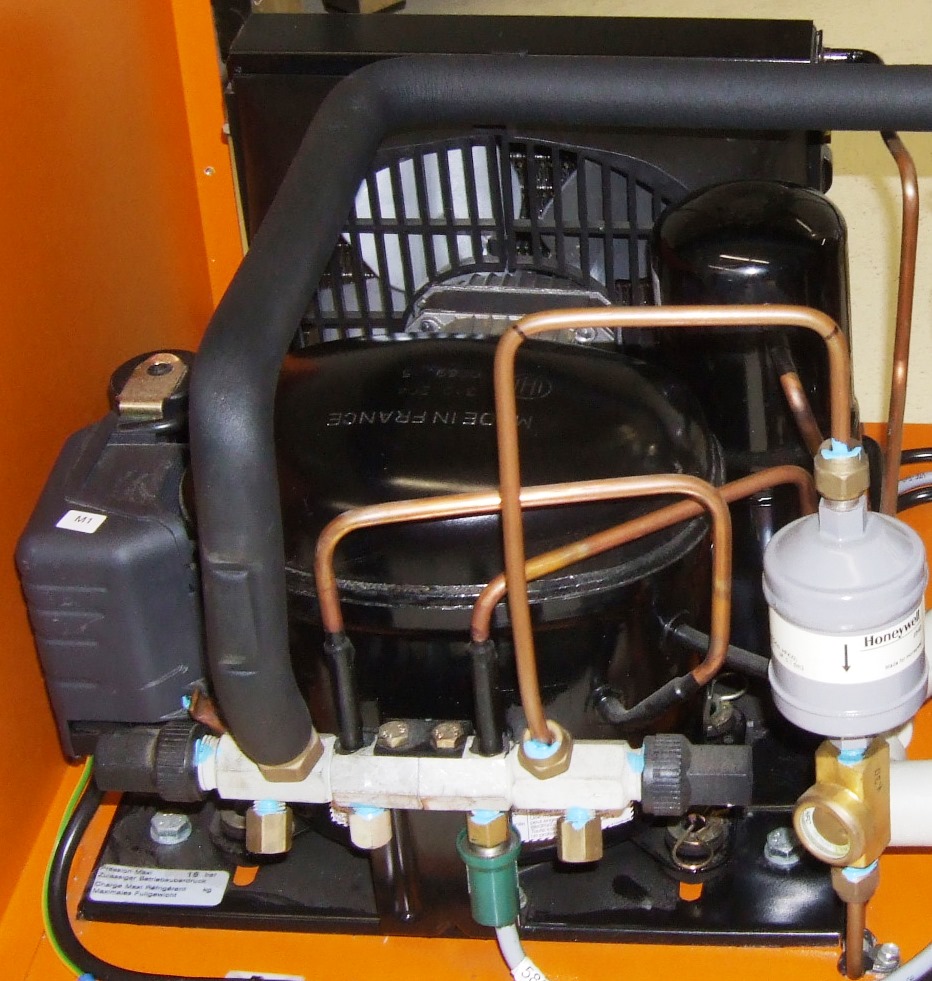 A real-world refrigeration condensing unit combining a compressor, condenser, and piping