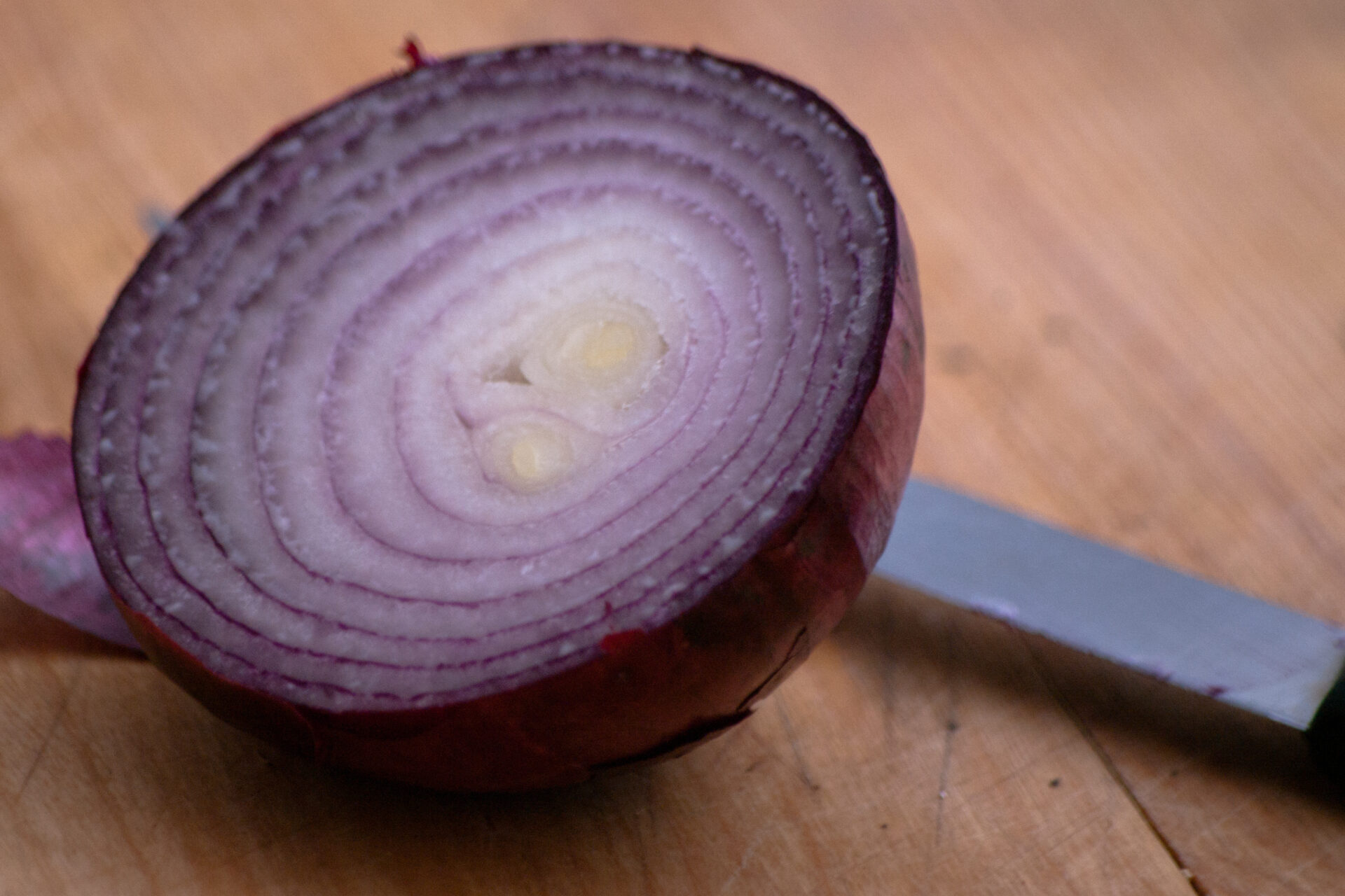 A red onion cut with a knife on a cutting board