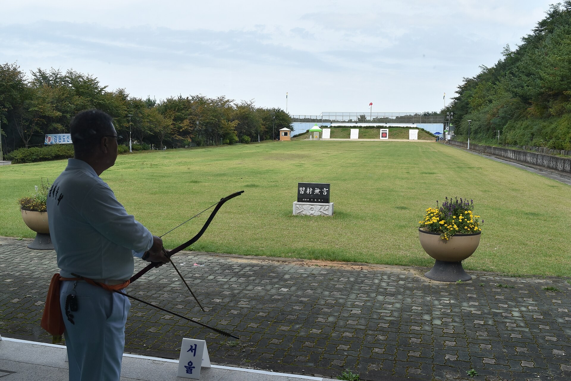 An archer at the shooting line with targets far across a wide lawn