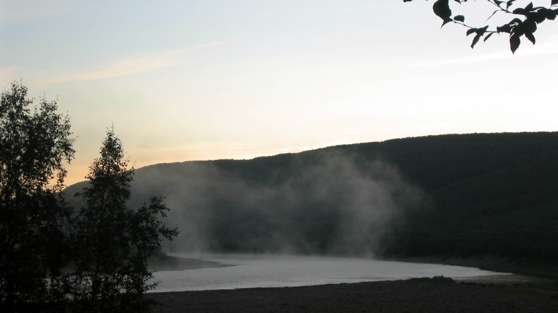 Wisps of fog over the Teno River against dark hills and trees