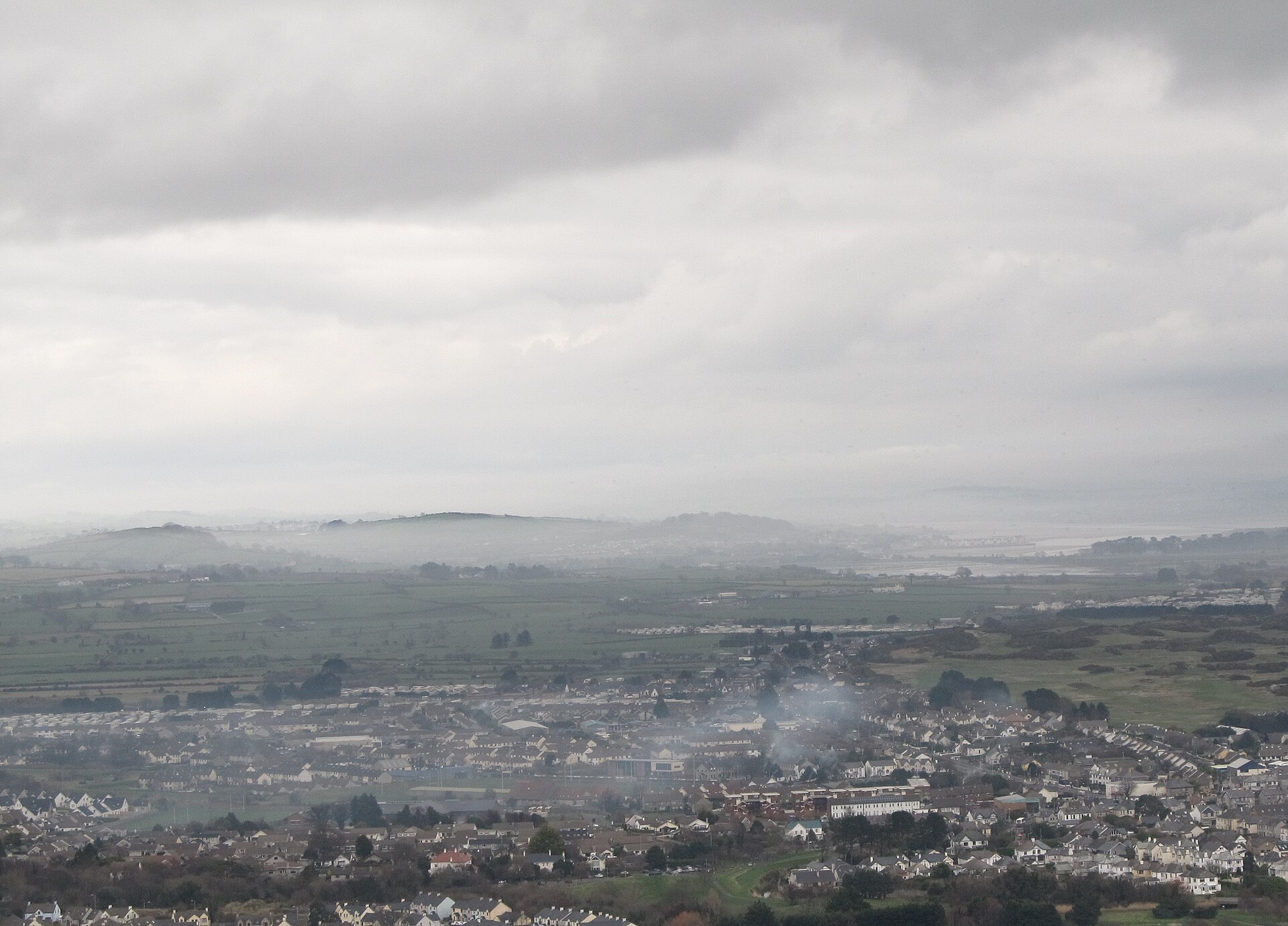 Low bands of fog across the Shimna and Carrigs valleys, above a town and fields