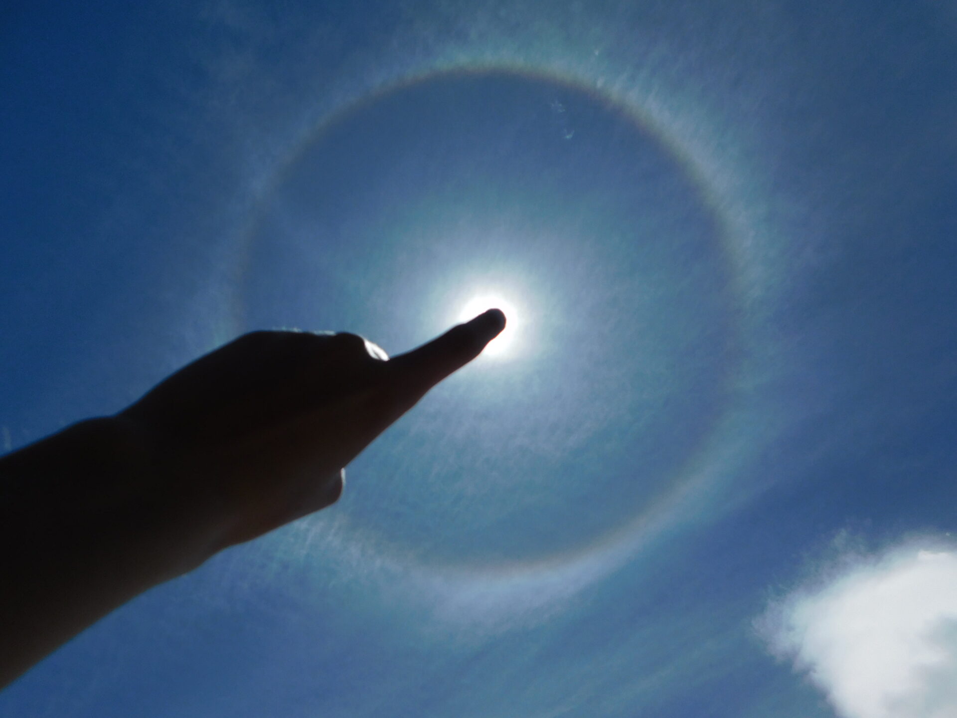 A broad solar halo with a finger covering the solar disk
