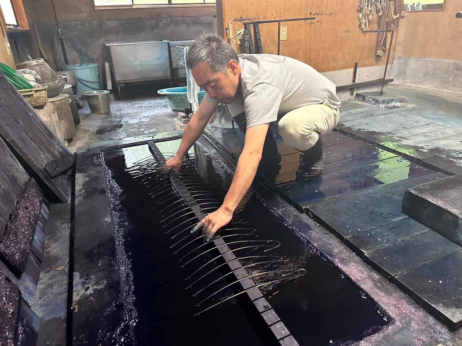 Matsubara Nobuo lowers a frame holding fabric into an indigo dye vat.