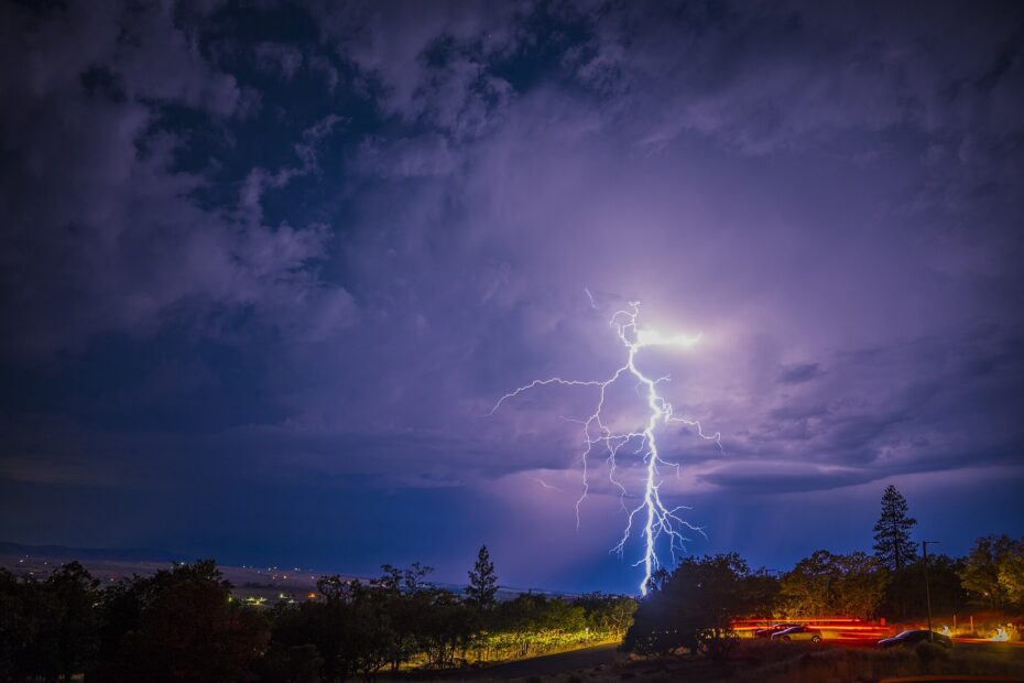 Branching lightning above trees and a road near Goldendale, Washington