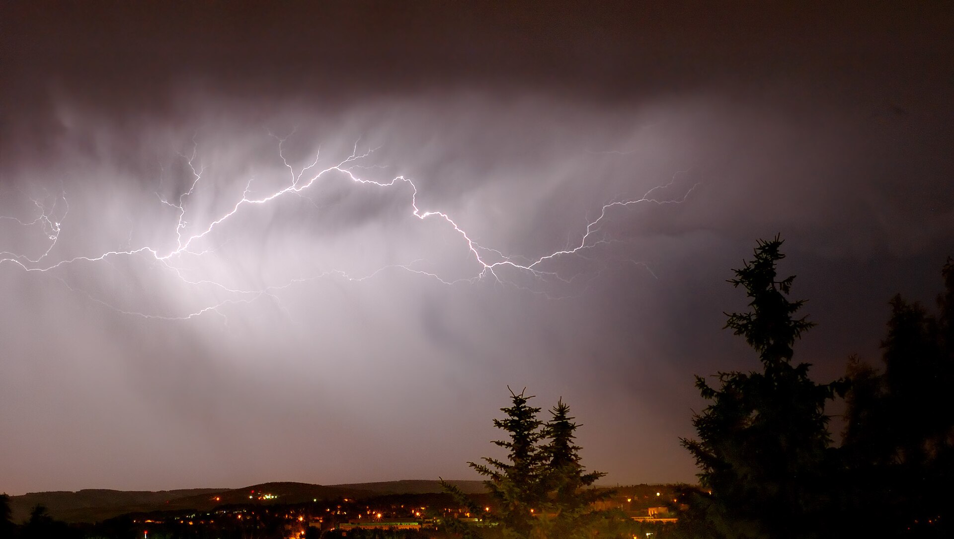 Branching lightning stretching across the sky above trees in Zwickau, Germany