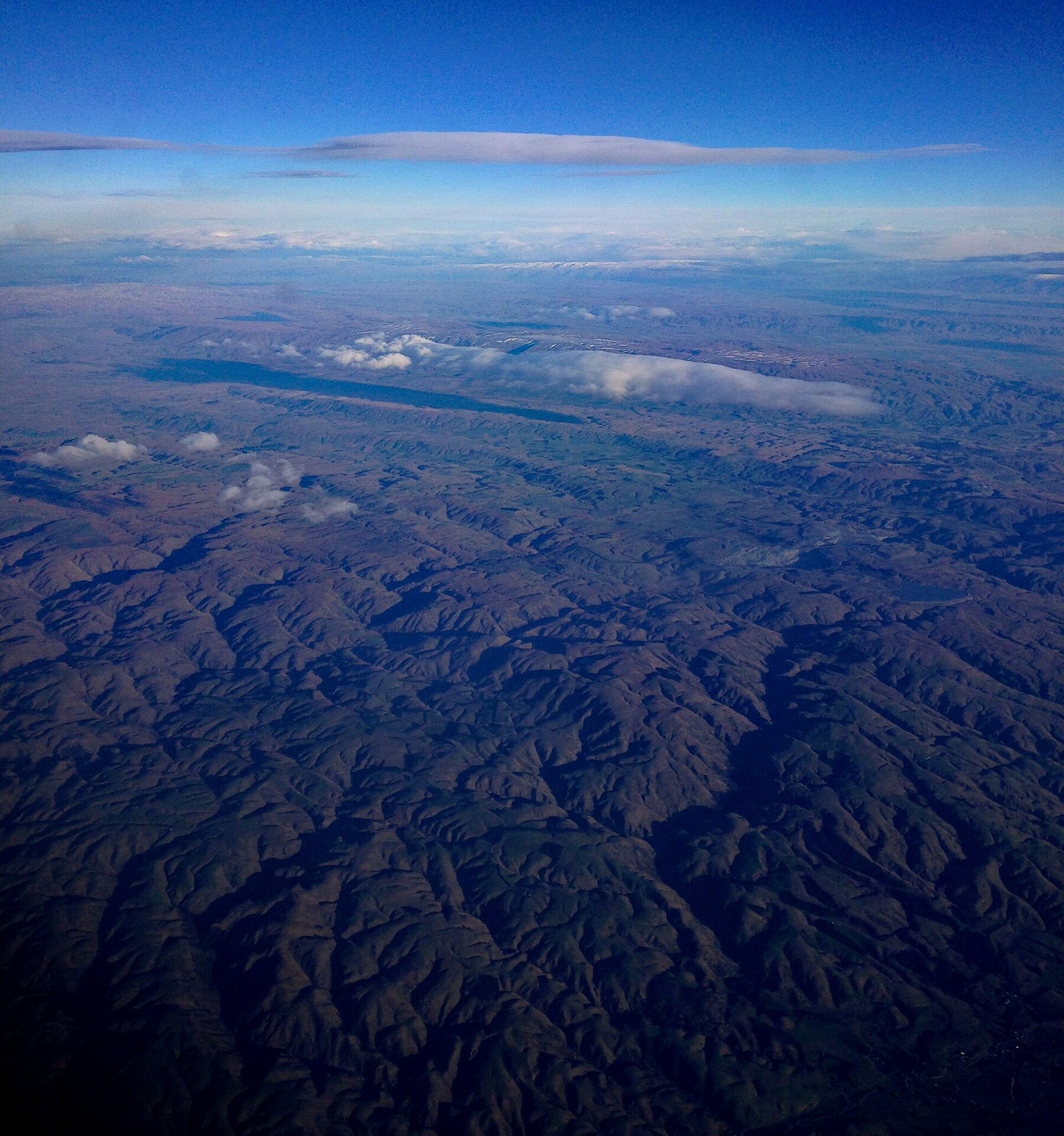 The long, flat Taieri Pet cloud above an aerial view of mountain terrain