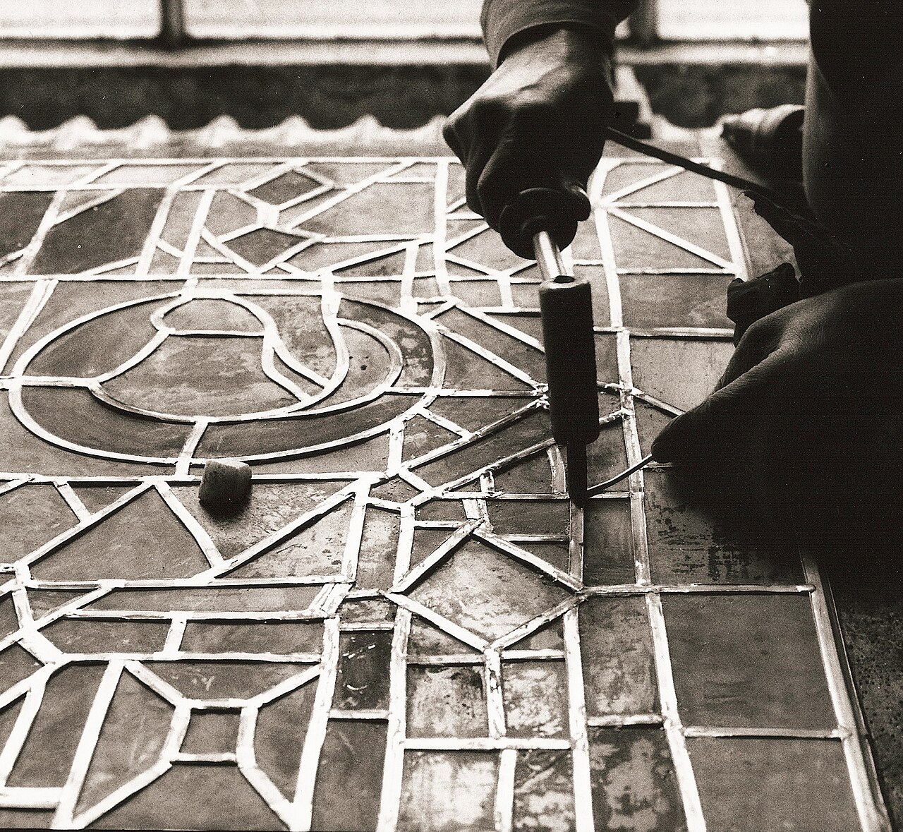 Soldering a metal junction in a stained-glass panel. The glass pieces themselves are not being melted together.